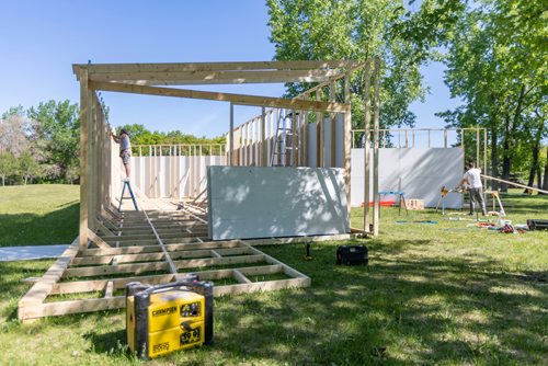 SASHA SEFTER / WINNIPEG FREE PRESS
Patrick Anderson works on the roof while Nick Kalturnyk cuts boards for a temporary venue in Parc Elzear Goulet in St. Boniface.
190613 - Thursday, June 13, 2019.