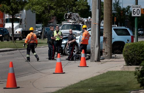 PHIL HOSSACK / WINNIPEG FREE PRESS - City police and Manitoba Hydro workers work to clear the scene of an accident at Burrows and Keewatin Tuesday. The incident left the intersection's north bound traffic detoured after traffic lights were left powerless. - June 18, 2019.