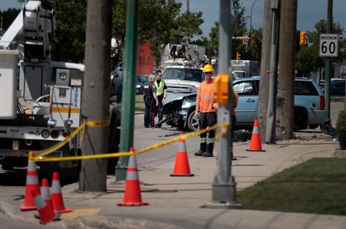 PHIL HOSSACK / WINNIPEG FREE PRESS - City police and Manitoba Hydro workers work to clear the scene of an accident at Burrows and Keewatin Tuesday. The incident left the intersection's north bound traffic detoured after traffic lights were left powerless. - June 18, 2019.