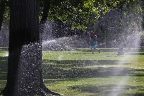 MIKE DEAL / WINNIPEG FREE PRESS
Sprinklers on the grounds of the Manitoba Legislative building forces brave morning foot traffic to sprint a few yards as they head downtown. 
190621 - Friday, June 21, 2019