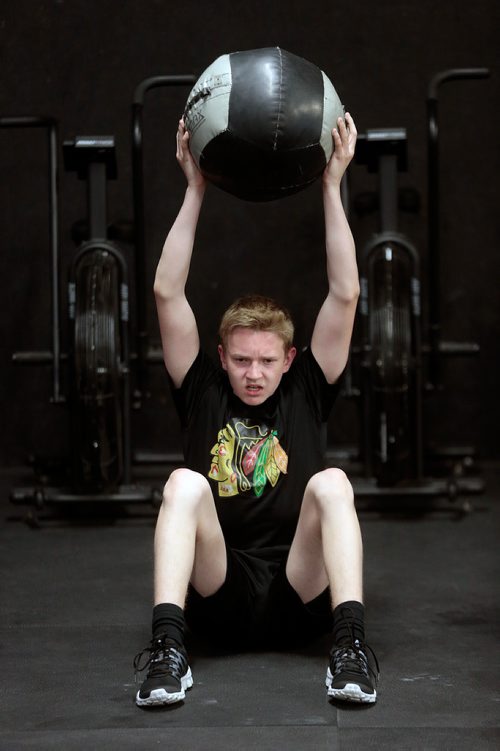 PHIL HOSSACK / WINNIPEG FREE PRESS -  Easton Lewicki does sit ups while lifting a medicine ball at the Cross Fit 204 Gym Wednesday evening. The 15 yr old teenager is part of a summer fitness program run by owner Ryan Stewart. See Sabrina Carnevale story.  - July 3, 2019.