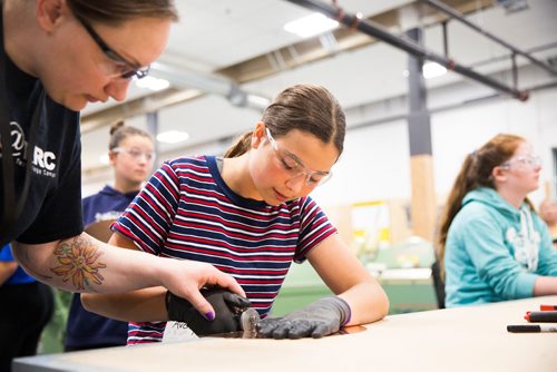 MIKAELA MACKENZIE / WINNIPEG FREE PRESS
Aubrey Doerksen, cabinetry and woodworking instructor, helps Avery Delaney, 14, scribe her piece of copper for a lamp base at the Girls Exploring Trades and Technology at Red River College in Winnipeg on Tuesday, July 9, 2019. For Nadya Pankiw story.
Winnipeg Free Press 2019.