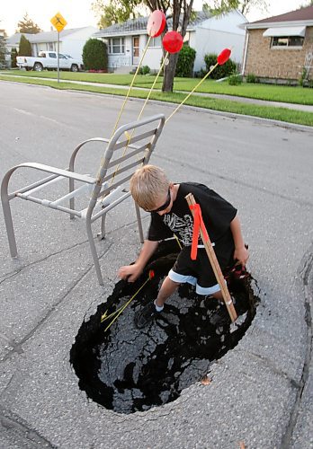 BORIS.MINKEVICH@FREEPRESS.MB.CA BORIS MINKEVICH / WINNIPEG FREE PRESS  090701 A pot hole on Robin Hood Cres. Jaxx Jowett,7, near/in the pothole that appeared Saturday night. They marked the hole so cars wouldn't drive into it.