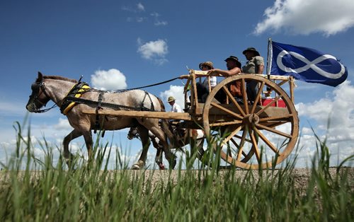 Brandon Sun 06072009 One of two solid oak Red River carts, driven by members of the Red River Métis Heritage Group and accompanied by other members on horseback, make their way towards Harmsworth, Man. on the first day of their journey to Fort Ellice.  (Tim Smith/Brandon Sun)