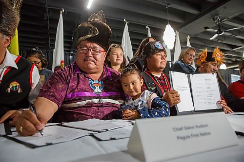 MIKE DEAL / WINNIPEG FREE PRESS
Glenn Hudson, Peguis First Nation, with his granddaughter, Emmy Neault, signs documents along with the other Treaty One First Nations Chiefs and Jim Carr, Minister of International Trade Diversification during the official announcement and signing over of the former Kapyong Barracks to Treaty One First Nations at a ceremony at the Assiniboia Downs Friday morning. 
190830 - Friday, August 30, 2019.