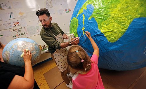 PHIL HOSSACK / WINNIPEG FREE PRESS -  Art City's Art Director Eddy Ayoub (centre) looks for references on an actual globe while 8 yr old Emma Loshakova paints Cuba on a giant paper mâché globe Tuesday afternoon preparing to participate in the Global Climate Strike to be held here Friday. Eva's story. - September 24, 2019.