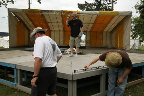 Brandon Sun Richard Harby (left), Dave McLean and John Scott (centre) help set up the main stage Thursday afternoon for this weekend's Brandon Folk, Music and Art Festival at the Keystone Centre grounds. The gate opens at 6:30 p.m. today for the festival's 25th anniversary. (Colin Corneau/Brandon Sun)