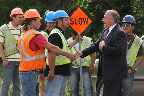 Brandon Sun Infrastructure and Transportation Minister Ron Lemieux greets a group of construction workers at the foot of the new 18th Street bridge during Thursday morning's official opening of the first of two bridges to replace the aging Thompson Bridge. (Bruce Bumstead/Brandon Sun)