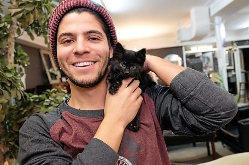 Daniel Crump / Winnipeg Free Press. Charles DaSilva, an employee at the MCC Furniture Thrift Shop on Keewatin Street, poses with Poly, the shops seven-month-old polydactyl kitten. November 7, 2019.