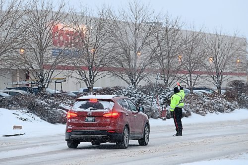 Mike Sudoma / Winnipeg Free Press
A police officer directs traffic outside of Costco along St James St Friday evening as rush hour traffic starts to pick up
December 13, 2019