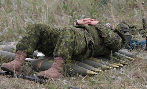 Brandon Sun And the Waiting Begins--Master Bombardier Mike Wiseman rest on top  155mm shells as "E" troop waits for their fire mission. (Bruce Bumstead/Brandon Sun)