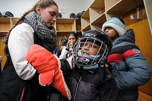 Daniel Crump / Winnipeg Free Press. Sefras Takeia (middle) is fitted for a helmet. The youngster is getting ready to try skating for the first time at the True North Youth Foundation's Welcome to Winnipeg event at Camp Manitou. January 11, 2020.