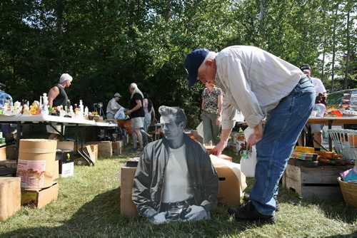 Brandon Sun 06092009 A cardboard cut-out of James Dean rests on the ground as bargain hunters shop during the 25th Anniversary Dunrea Antique Flea Market on Sunday afternoon. Marchuk has almost every single style of Manitoba licence plate ever issued. along with many other collectables.  (Tim Smith/Brandon Sun)