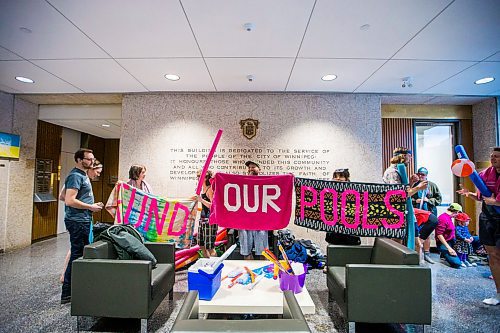 MIKAELA MACKENZIE / WINNIPEG FREE PRESS

Members of Budget for All Winnipeg hold up beach towel signs at a "pool party" in the lobby of City Hall in protest of proposed budget cuts to city pools and recreation facilities in Winnipeg on Thursday, Jan. 30, 2020. For Danielle Da Silva story.
Winnipeg Free Press 2019.