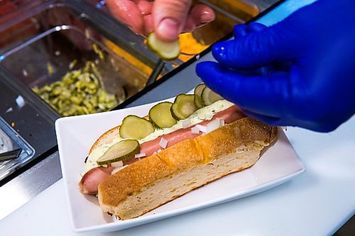 MIKAELA MACKENZIE / WINNIPEG FREE PRESS

Co-owner of Wienerpeg, Quin Ferguson, puts toppings on a hot dog at the new gourmet hot dog vendor at The Forks, in Winnipeg on Tuesday, Feb. 11, 2020. For biz story.
Winnipeg Free Press 2019.