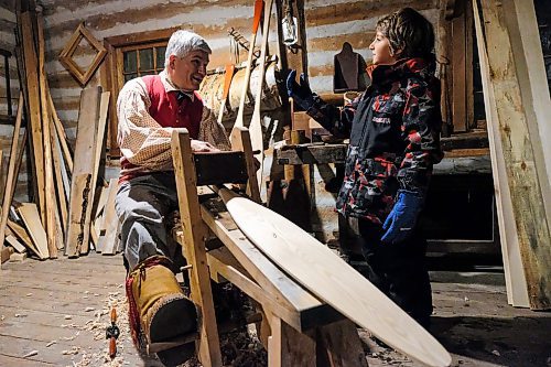 Daniel Crump / Winnipeg Free Press. Seven-year-old Samuel Budniok (right) interacts with Mark Blieske (left) who demonstrates the traditional way to make wooden canoe paddles on opening night of Festival Du Voyageur. February 14, 2020.