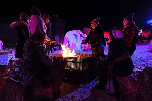 Daniel Crump / Winnipeg Free Press. Evelyn Green (middle) warms her hands by a fire on opening night of Festival Du Voyageur. February 14, 2020.