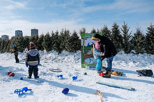 Daniel Crump / Winnipeg Free Press. Mark Dixon (right) helps his daughter Hazel figure out how to use cup stilts as kids play games at Festival du Voyageur on Saturday. February 15, 2020.