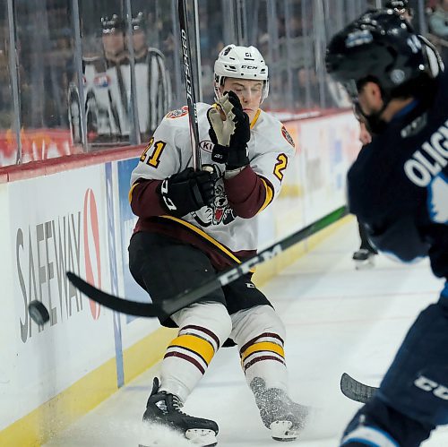 Phil Hossack / Winnipeg Free Press - Chicago Wolves #21 Ben Jones recoils from a clearing shot by Manitoba Moose defenceman #14 Jimmy Oligny Saturday afternoon. February 29, 2020