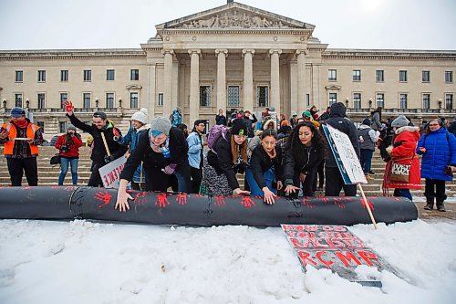 MIKE DEAL / WINNIPEG FREE PRESS
Students put a red hand print onto a large cardboard "pipeline" during a rally outside the Manitoba Legislature over the noon hour as part of a nationwide student walk-out in solidarity with Wetsuweten hereditary chiefs Wednesday.
200304 - Wednesday, March 04, 2020.