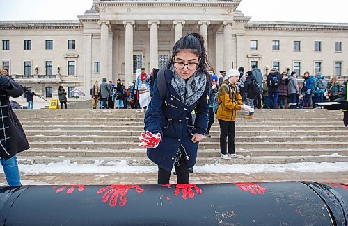 MIKE DEAL / WINNIPEG FREE PRESS
University of Winnipeg student, Sanjam Panag, puts a red hand print onto a large cardboard "pipeline" during a rally outside the Manitoba Legislature over the noon hour as part of a nationwide student walk-out in solidarity with Wetsuweten hereditary chiefs Wednesday.
200304 - Wednesday, March 04, 2020.