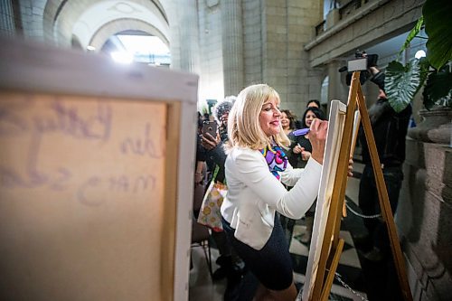 MIKAELA MACKENZIE / WINNIPEG FREE PRESS

Cathy Cox, minister responsible for the status of women, writes the name of a woman who inspires her (her Baba) on a canvas at the Manitoba Legislative Building in Winnipeg on International Women's Day, Monday, March 9, 2020. 
Winnipeg Free Press 2019.