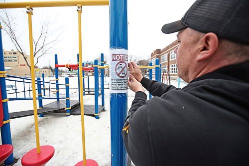 MIKE DEAL / WINNIPEG FREE PRESS
A Winnipeg School Division maintenance worker puts up a sign on an empty playground at Mulvey School Tuesday morning. 
The Manitoba School Boards Association has recommended all provincial schools close their play structures on school grounds immediately to adhere to social distancing guidelines. MSBA said the use of such equipment is "prohibited" indefinitely, although it encourages families to play in open spaces near community and school playgrounds. The Winnipeg School Division is currently in the process of putting up signage and removing swings in all of its 89 school playgrounds.
200324 - Tuesday, March 24, 2020