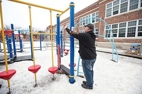 MIKE DEAL / WINNIPEG FREE PRESS
A Winnipeg School Division maintenance worker puts up a sign on an empty playground at Mulvey School Tuesday morning. 
The Manitoba School Boards Association has recommended all provincial schools close their play structures on school grounds immediately to adhere to social distancing guidelines. MSBA said the use of such equipment is "prohibited" indefinitely, although it encourages families to play in open spaces near community and school playgrounds. The Winnipeg School Division is currently in the process of putting up signage and removing swings in all of its 89 school playgrounds.
200324 - Tuesday, March 24, 2020