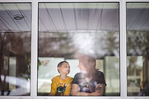 MIKAELA MACKENZIE / WINNIPEG FREE PRESS

Stacey Abramson, high school art teacher, poses in a window in her house with her son, Louis Chevrefils, 6, in Winnipeg on Thursday, March 26, 2020. She's been self-isolated since March 14th, and sent out a drawing prompt to some of her classes to find inspiration by drawing the view from their windows.
Winnipeg Free Press 2020