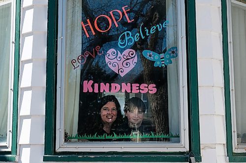 Daniel Crump / Winnipeg Free Press. Leigh Nash (left) and Zachary Kruger (right) pose in a window of their home which they have decorated with positive messages to cheer up their neighbourhood. March 28, 2020.