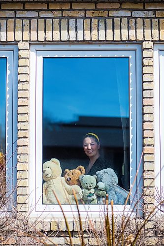 MIKAELA MACKENZIE / WINNIPEG FREE PRESS

Sheilah Restall, who sparked a new initiative called the Great Winnipeg Bear Hunt, poses for a portrait in her front window in Winnipeg on Monday, March 30, 2020. She's encouraging Winnipeggers to put teddy bears in their windows to give kids something to hunt for on neighbourhood walks.
Winnipeg Free Press 2020