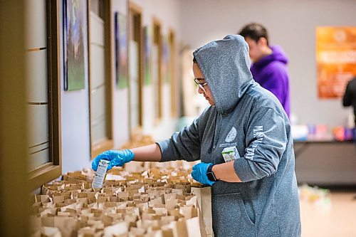 MIKAELA MACKENZIE / WINNIPEG FREE PRESS

Volunteer Tempest Bruce puts juice, snacks, and fruit into meal packages for emergency kits with food, hygiene and baby products at Ma Mawi Wi Chi Itata in Winnipeg on Monday, March 30, 2020. For Eva Wasney story.
Winnipeg Free Press 2020