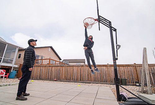 Mike Sudoma / Winnipeg Free Press
Team Manitoba Basketball guard, Lorence dela Cruz dunks (right) as his trainer, Anthony Carino watches in Lorences backyard court Tuesday afternoon
April 14, 2020