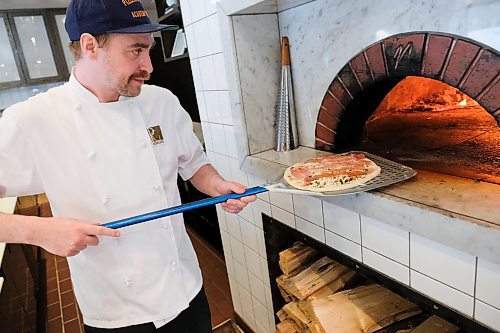 Daniel Crump / Winnipeg Free Press. Greg Cavers, pizza chef at Pizzeria Gusto, slide a pizza into a wood fired oven. April 30, 2020.