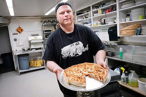 Daniel Crump / Winnipeg Free Press. Marc Vercuysse, of Bulldog Pizza holds a meat lovers deepish pie while standing for a photo in the kitchen of his restaurant. April 30, 2020.