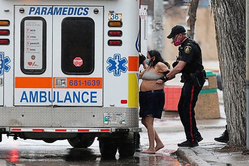 SHANNON VANRAES / WINNIPEG FREE PRESS
Police escort a woman to a waiting ambulance near the intersection of Sherbrook St. And Broadway on May 1, 2020.