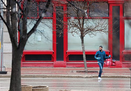 SHANNON VANRAES / WINNIPEG FREE PRESS
A man wearing gloves and carrying a Skip The Dishes delivery bag crosses King St. in Winnipeg's Exchange District on May 1, 2020.