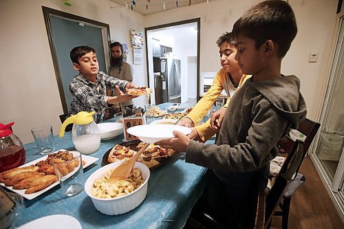 JOHN WOODS / WINNIPEG FREE PRESS
Usaid Habib hands some pizza to his brothers Fahad,right, and Mahad. Urooj Danish and her family break their Ramadan fast with prayers and an iftar meal at sundown in her home Wednesday, May 6, 2020. 

Reporter: May/Part of 24 hr life during COVID-19 project