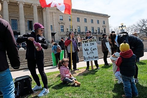 Daniel Crump / Winnipeg Free Press. Kids play in front of people holding signs at an anti-lockdown protest at the Manitoba Legislature. Social distancing and other safety protocols were not followed, or enforced. May 9, 2020.