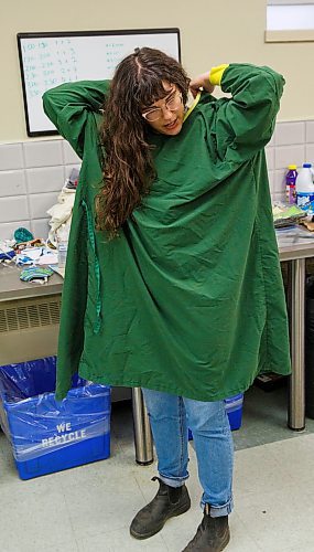 MIKE DEAL / WINNIPEG FREE PRESS
Volunteer Caileigh Morrison at 1JustCity, 365 McGee Street, an organization that operates three drop-in centres in Winnipeg. Caileigh puts on freshly laundered PPE for her shift at the drop-in centre.
200514 - Thursday, May 14, 2020.
