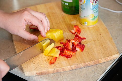 Mike Sudoma / Winnipeg Free Press
Elsa Taylor, head bartender and co-owner of The Roost, cuts up some Strawberries, Pineapple as she makes her Amped up Gin and Soda in her apartment Saturday afternoon
May 23, 2020