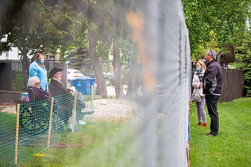 MIKAELA MACKENZIE / WINNIPEG FREE PRESS

Cheryl Hedlund and Chris Siddorn visit Cheryl's parents, Ron and Anne Fetterly, through the fence at Oakview Place care home (as employee Traci Schludermann facilitates the visit) in Winnipeg on Friday, May 29, 2020. For Eva Wasney story.
Winnipeg Free Press 2020.