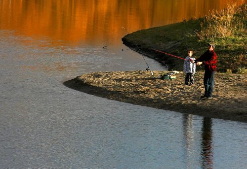 Brandon Sun The autum colours reflect off the water  behind a father and son fishing on the Assinboine River on Thursday afternoon. (Bruce Bumstead/Brandon Sun)