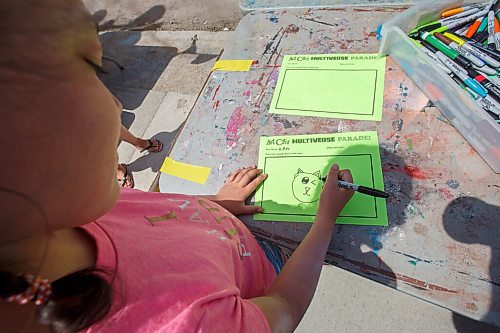 MIKE DEAL / WINNIPEG FREE PRESS
Zen Havard, 9, draws a picture which will be transferred to a sign, via the magic of video editing, that she will carry along the sidewalk in front of Art City. Everyone that drops by between noon and 2pm on June 15-19 will be added to a video being created by ArtCity. The Multiverse Parade video will show what normally is a large crowd of kids and supporters celebrating the end of the school year on one day in a video that will allow everyone to maintain social distancing during the coronavirus pandemic.
200616 - Tuesday, June 16, 2020.