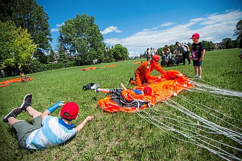 MIKAELA MACKENZIE / WINNIPEG FREE PRESS

Sargent Brandon Schetterer gets his son, Ryder Schetterer (five, left), and son's friends Blake Coulombe (five, centre), and Bryson Coulombe (seven, right) to roll over the parachute to get the air out while packing it up after a military search and rescue parachute demonstration in honour of front line workers into Sturgeon Creek Park in Winnipeg on Friday, June 19, 2020.  Standup.
Winnipeg Free Press 2020.