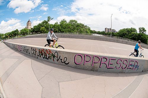 Mike Sudoma / Winnipeg Free Press
Cyclists bike by a graffiti tag reading No One is Free When Others Are Oppressed on the side of the pedestrian walkways on the Osborne Bridge Saturday morning
June 20, 2020