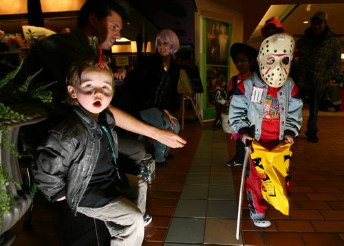Brandon Sun Four-year-old Michael Deveau, right,  makes the Halloween rounds at the the Town Centre making a stop at the Black Orchid salon where he received candy from Beverly and Robert Kuyszak and their son Mathew, left, on Friday afternoon. (Bruce Bumstead/Brandon Sun)