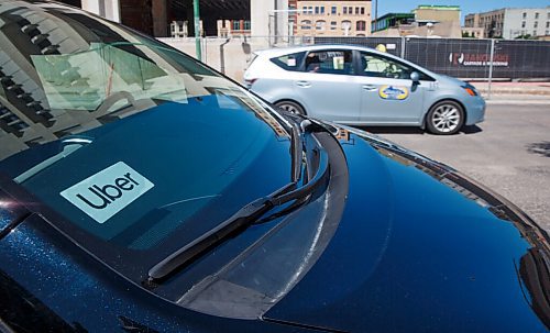 MIKE DEAL / WINNIPEG FREE PRESS
A taxi speeds by a vehicle with an Uber sticker in the window which is sitting outside City Hall for the announcement that the ride sharing service is open for business in Winnipeg as of today. 
200707 - Tuesday, July 07, 2020.