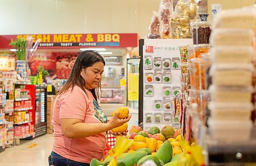 Mike Sudoma / Winnipeg Free Press
Maribeth Fernandez, a regular customer at Youngs Market, takes time to stop and grab some mangoes while shopping Friday afternoon
July 10, 2020