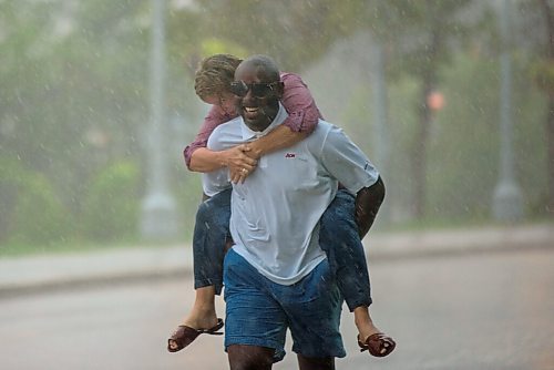 JESSE BOILY  / WINNIPEG FREE PRESS
A woman rides on a mans back during the rainstorm on Friday afternoon. Friday, July 17, 2020.
Reporter: